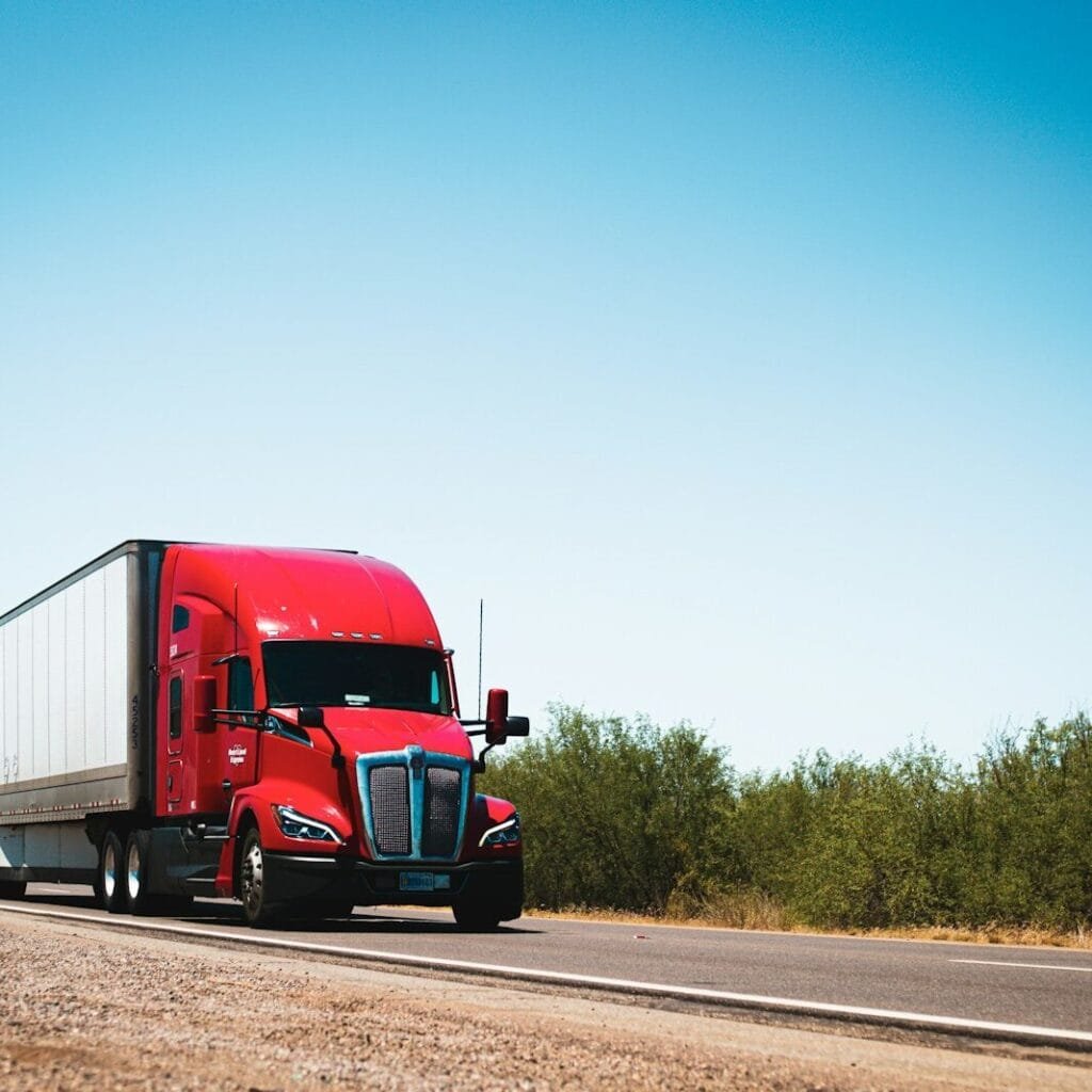 A red semi truck driving down a country road